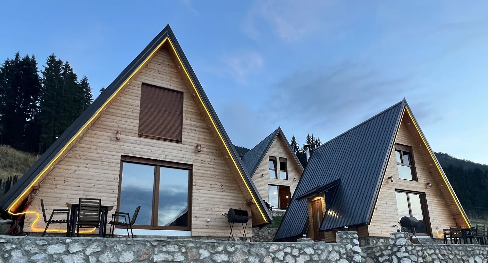 Three A-frames with glowing gables at dusk