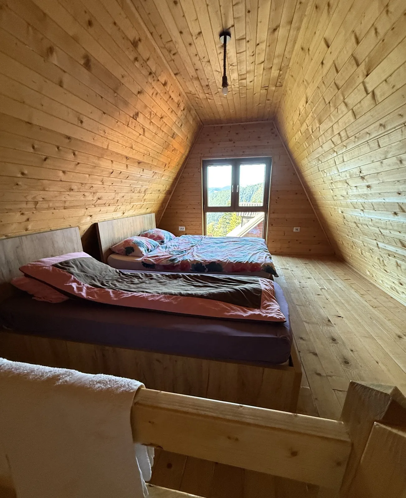 Loft bedroom with two beds under the sloping pine ceiling